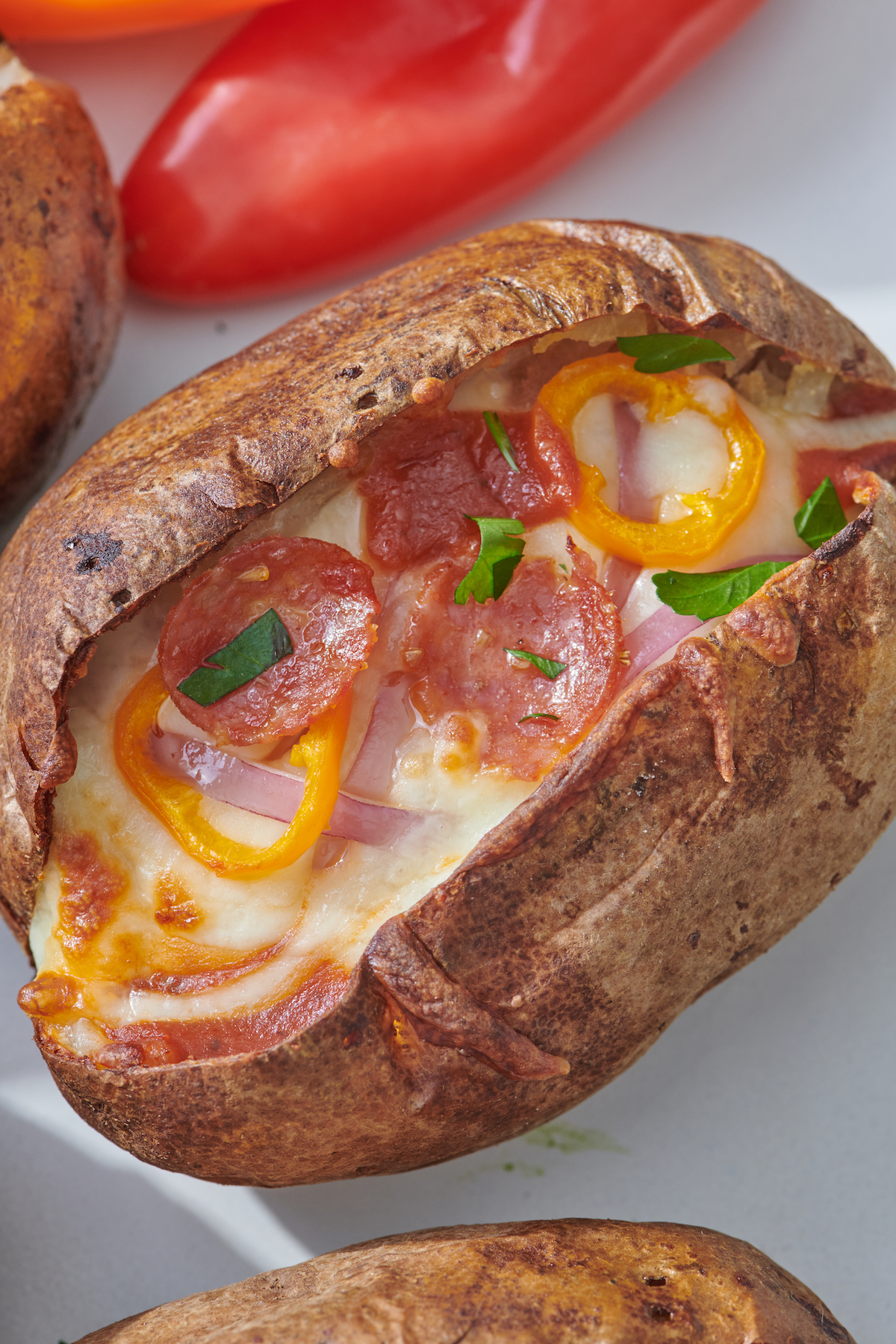 pepperoni, yellow peppers, red onion,  and cheese on baked potato