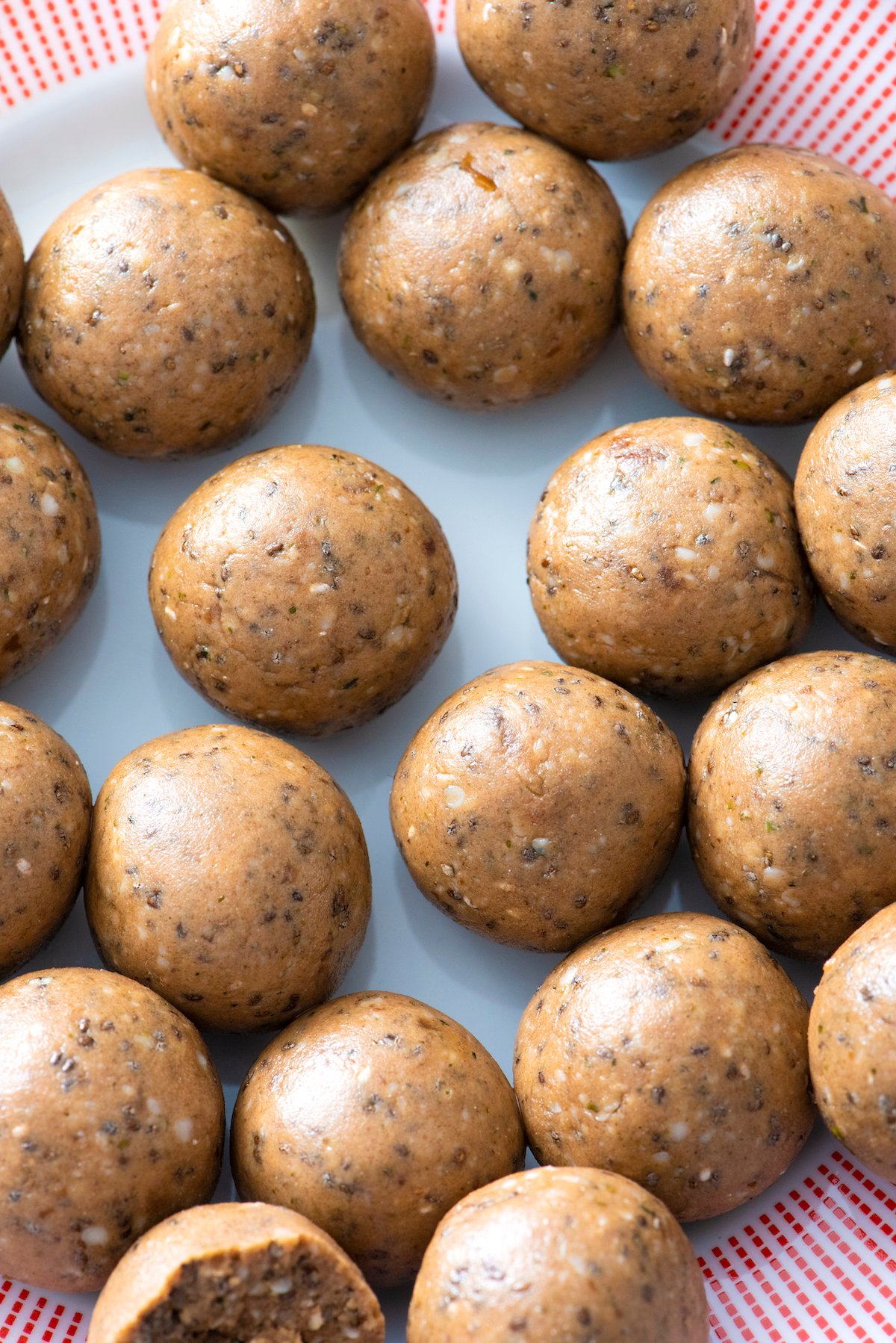 Close up of plain Protein Balls on a red-trimmed plate.
