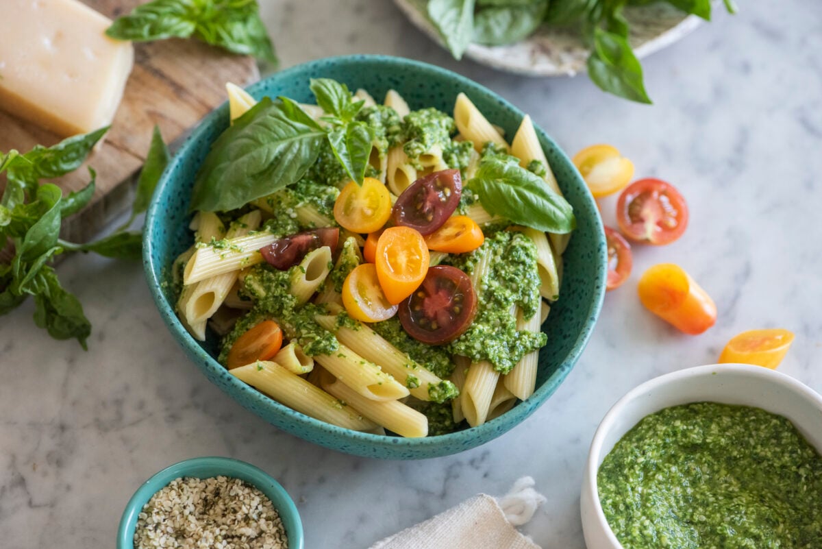 blue bowl with hemp seed pesto over pasta with cheery tomatoes