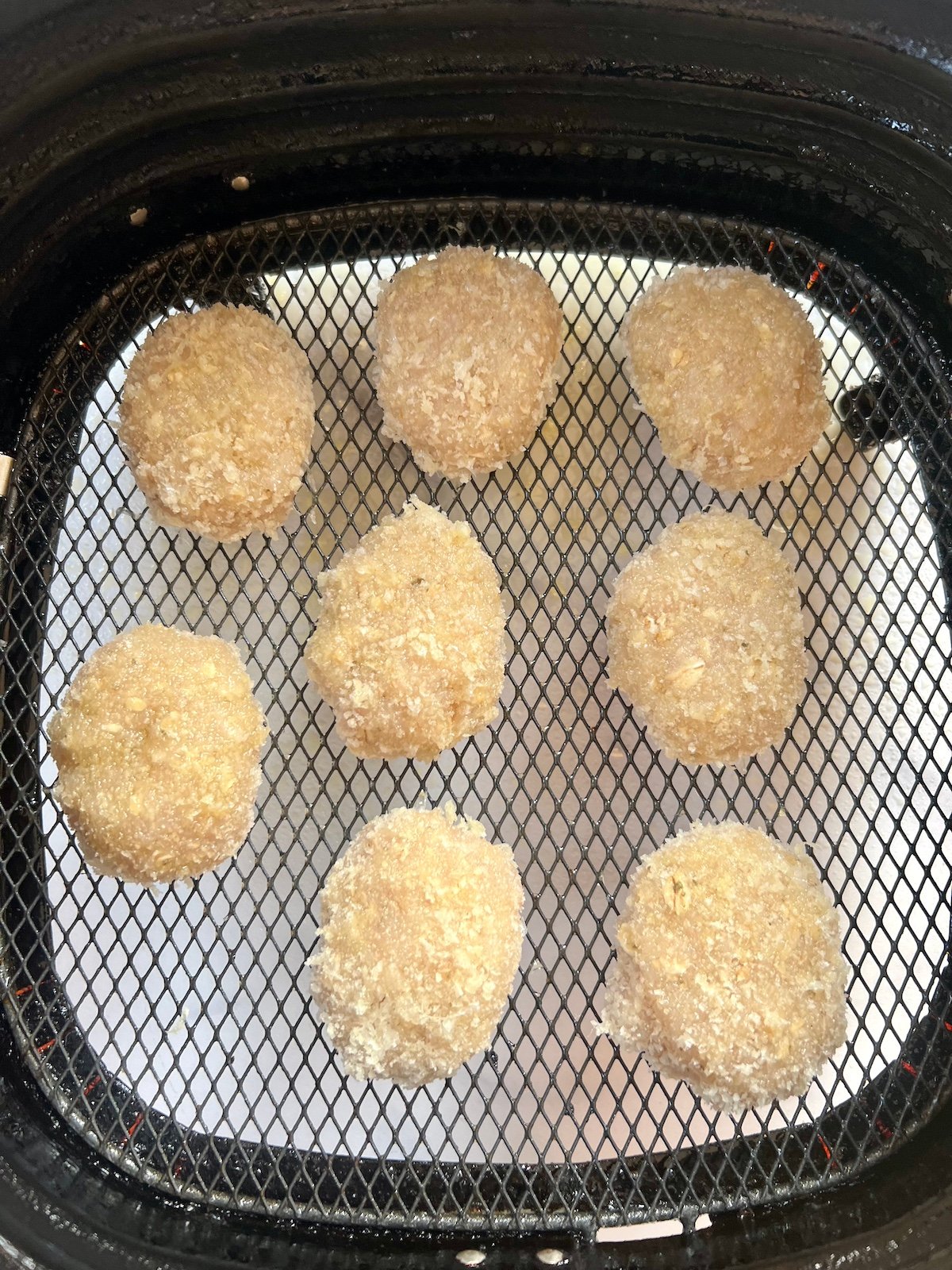 Chicken nuggets in air fryer basket.