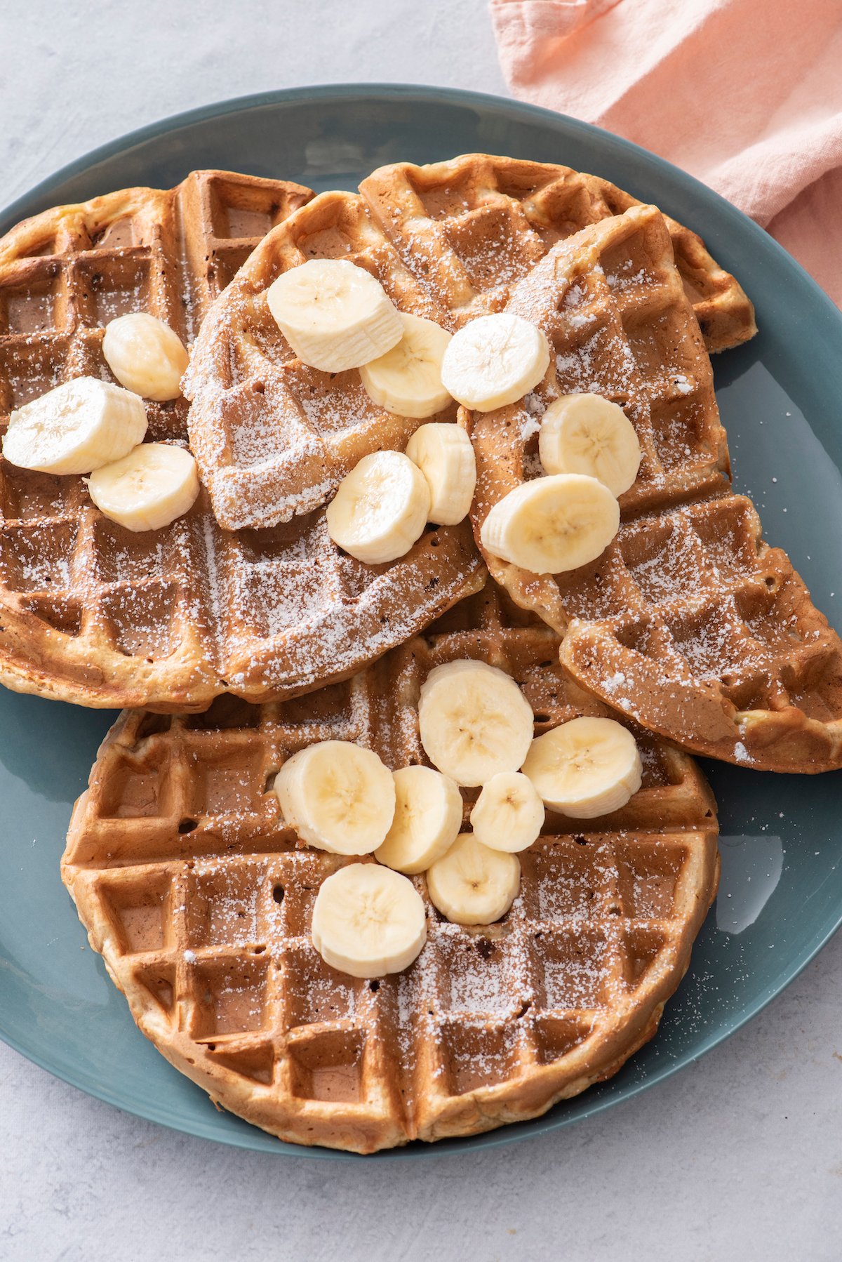 banana waffles topped with sliced bananas and powdered sugar