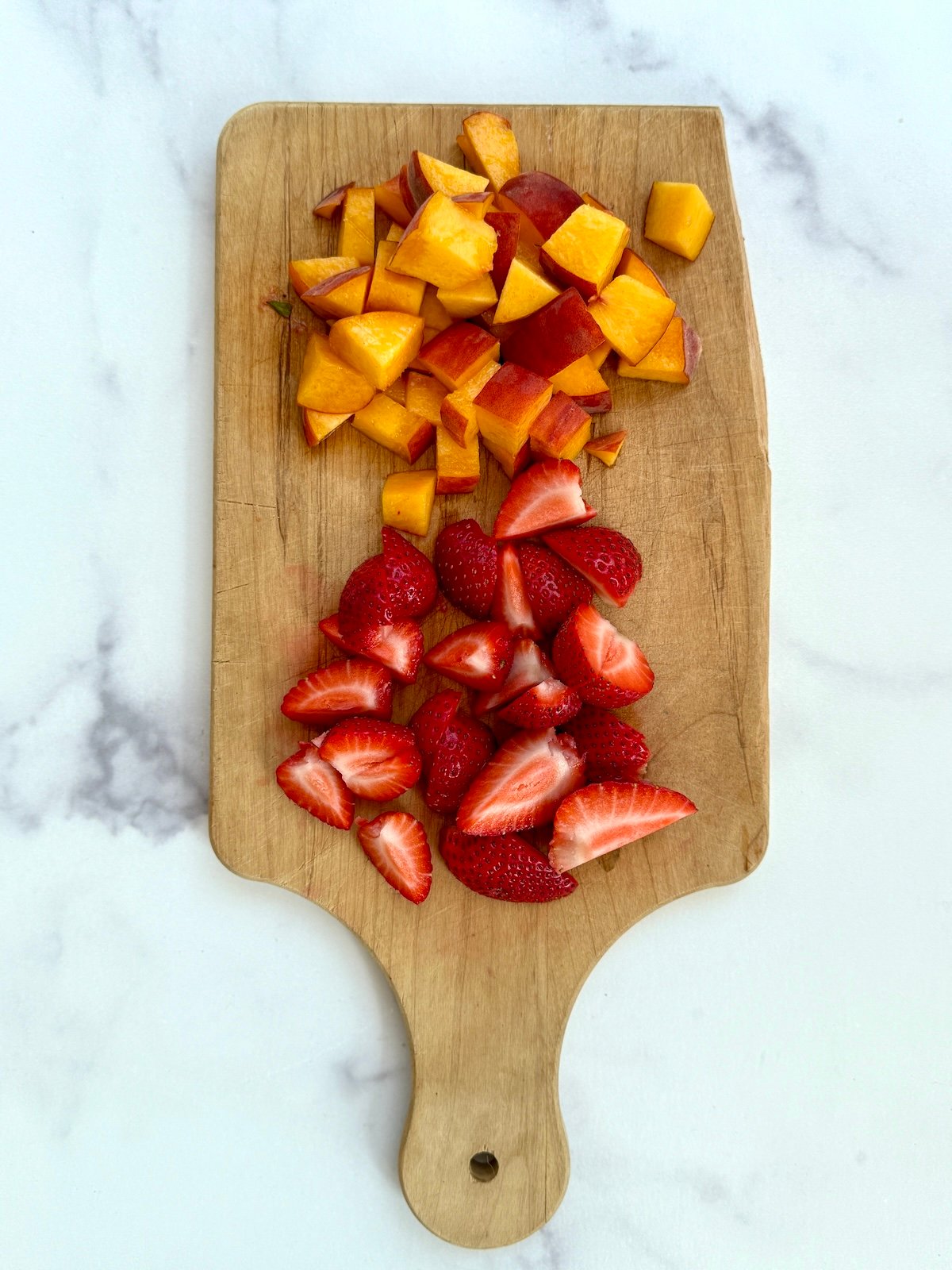 Cut up strawberries and peaches.