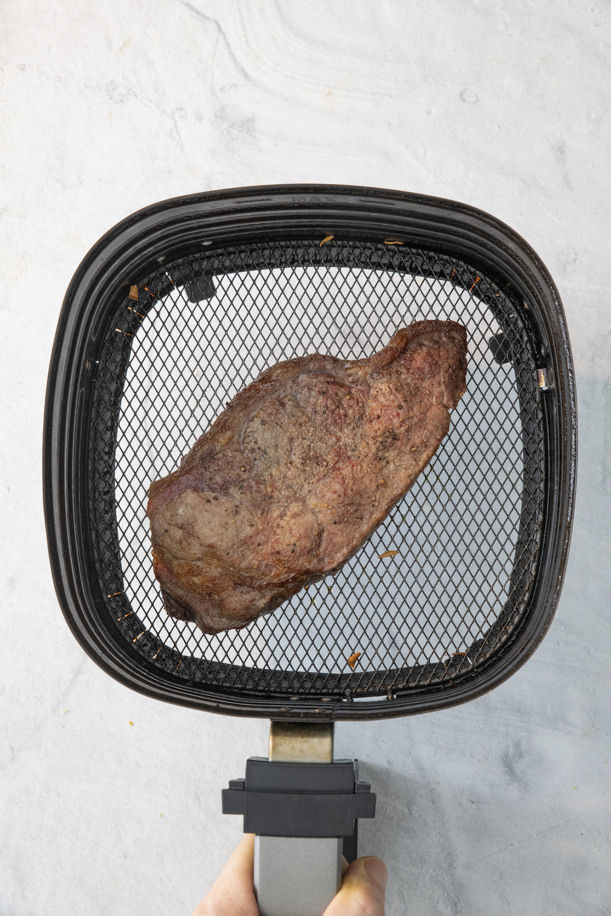 Steak in an air fryer basket.