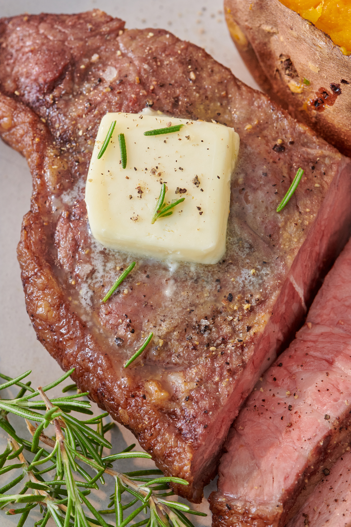 Close up of Air Fryer Steak topped with butter and fresh herbs.