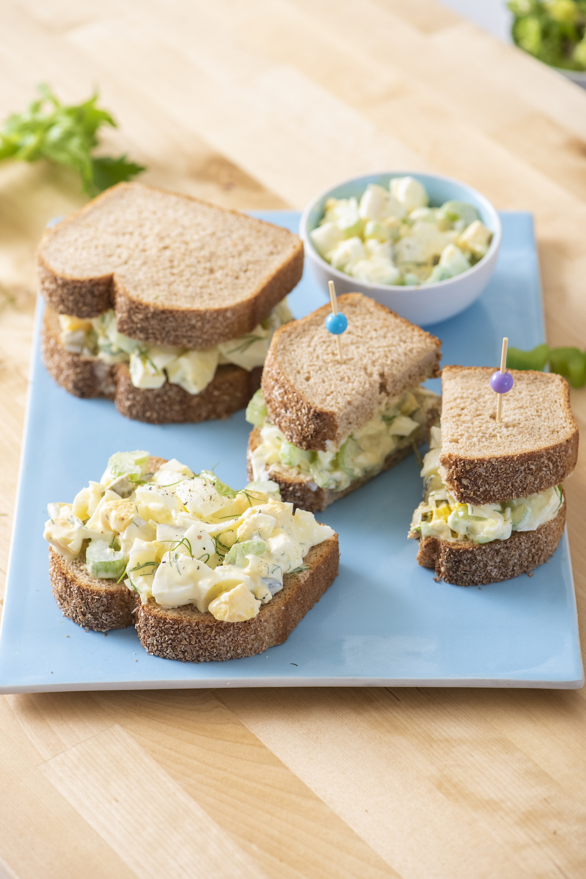 Three egg salad sandwiches on serving tray.