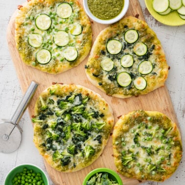 Pizzas with pesto and green veggies.