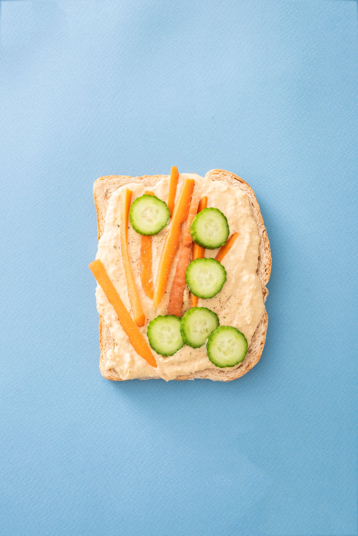 open face sandwich with hummus, carrots and cucumbers