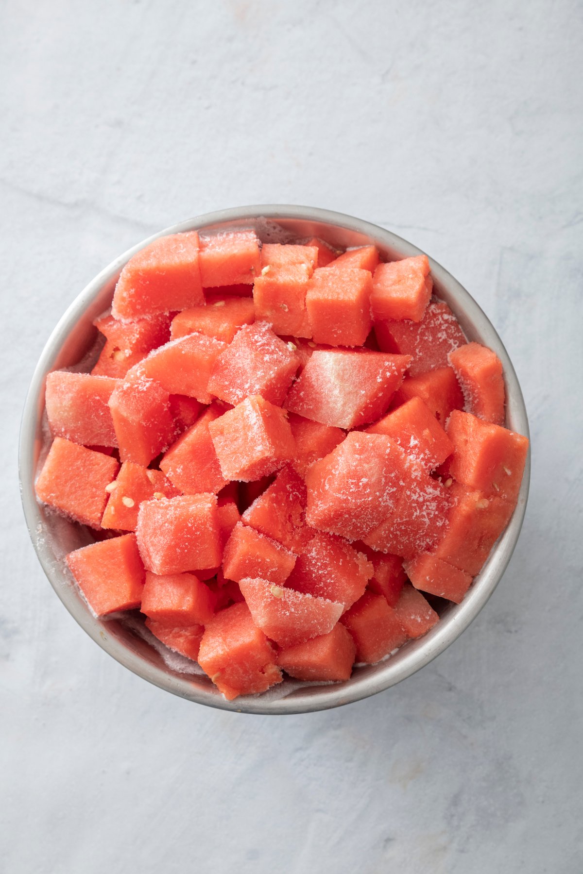 Frozen watermelon chunks in silver bowl.