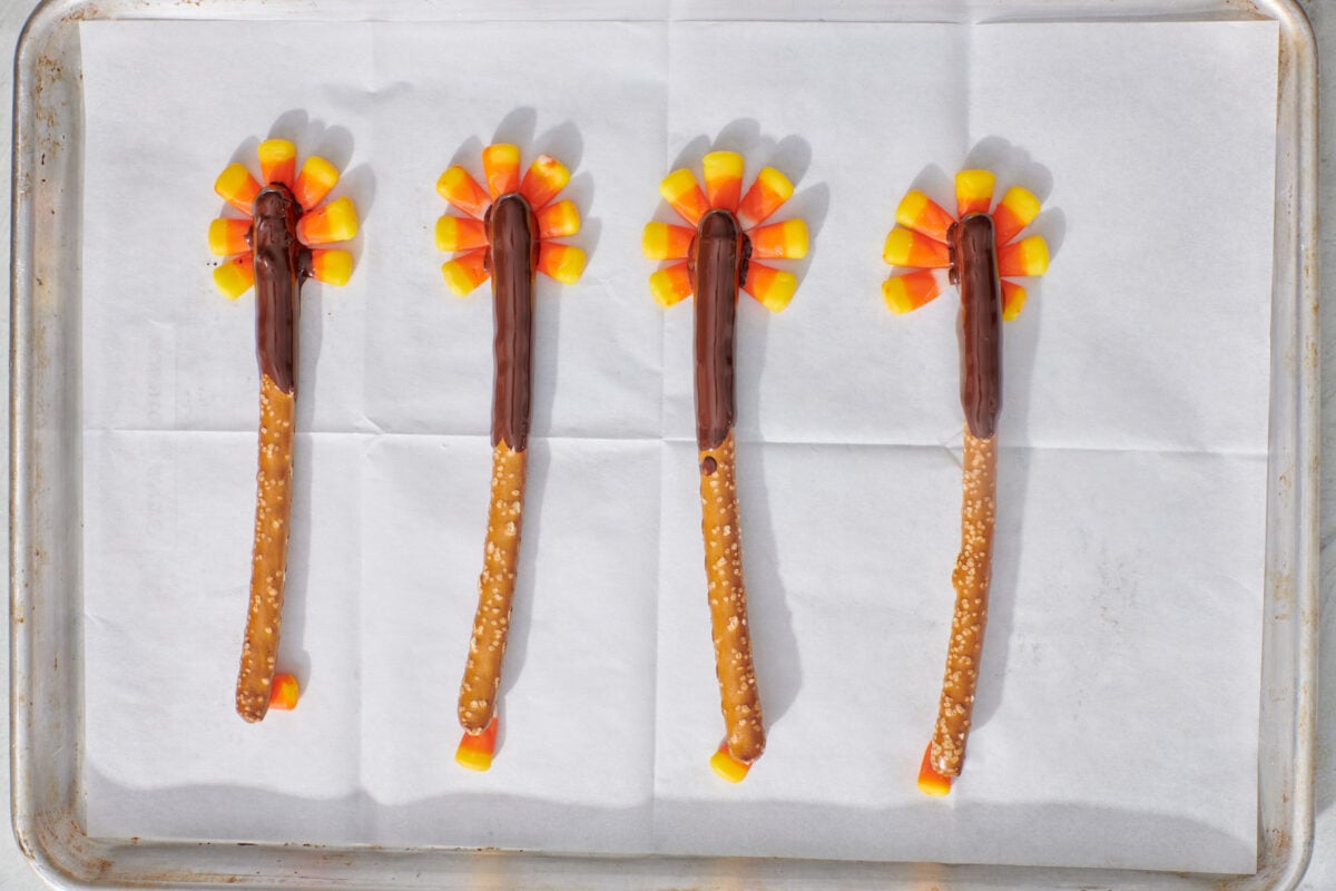 Chocolate dipped pretzel rods on top of candy corn "feathers".