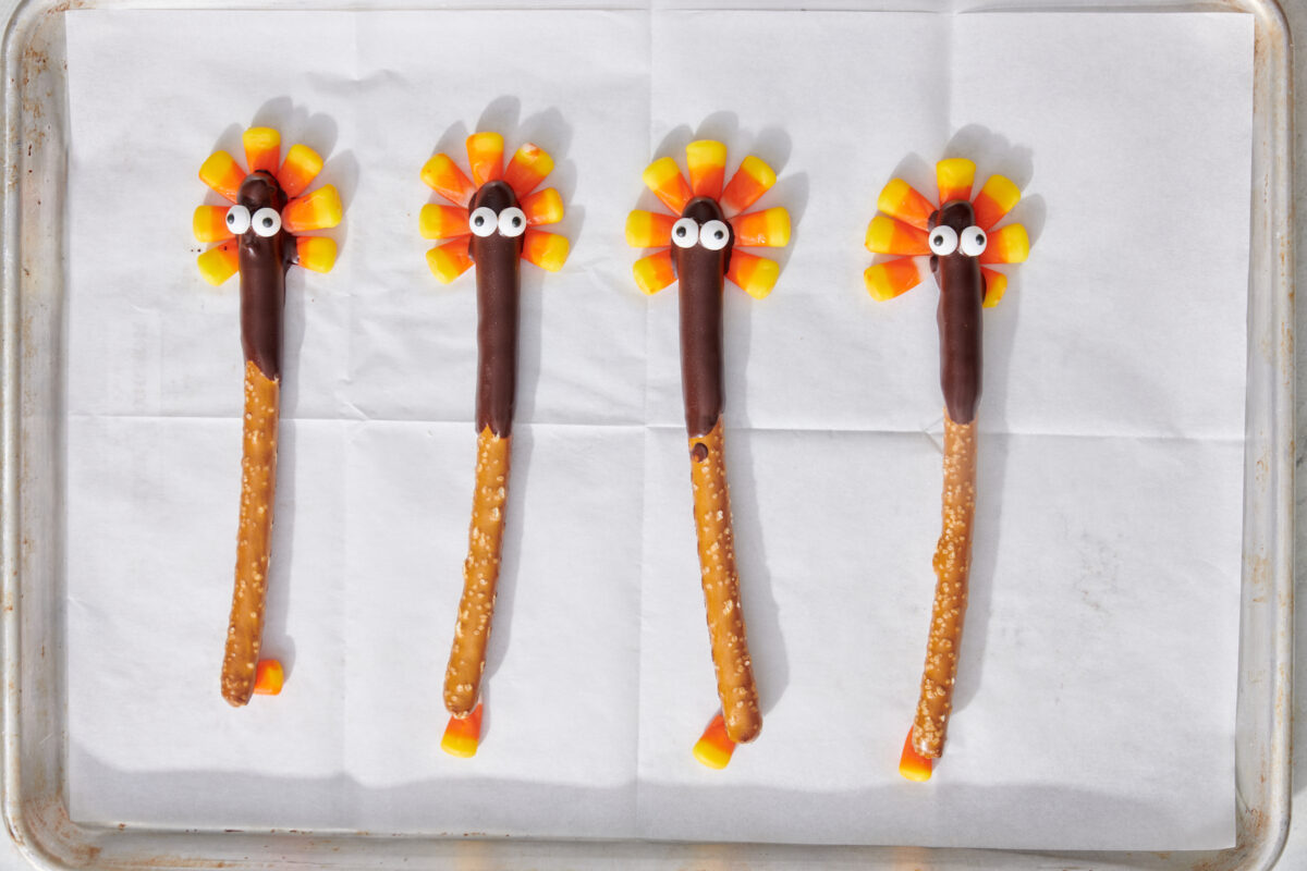 Chocolate covered pretzels with candy eyes on top of candy corn "feathers".