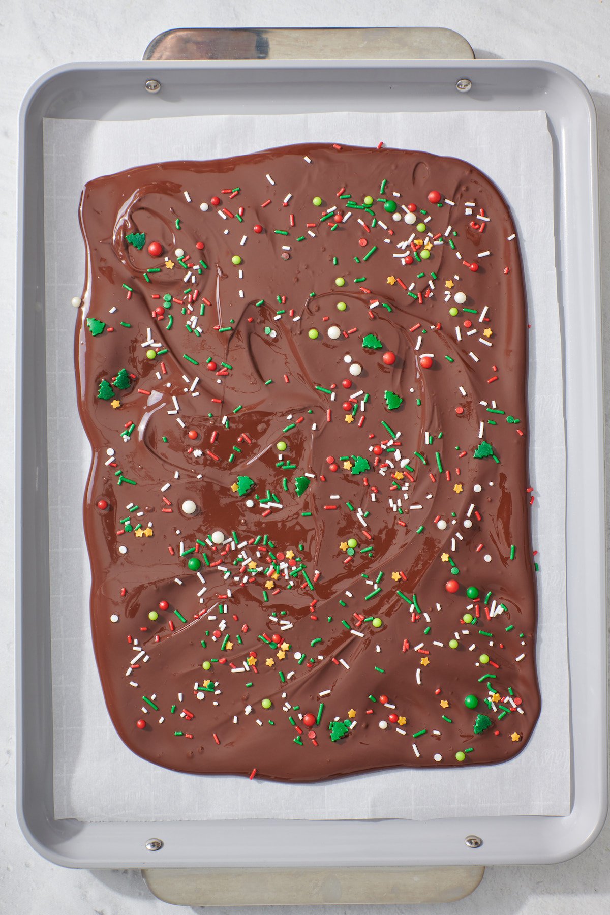 Melted chocolate on baking sheet with sprinkles.