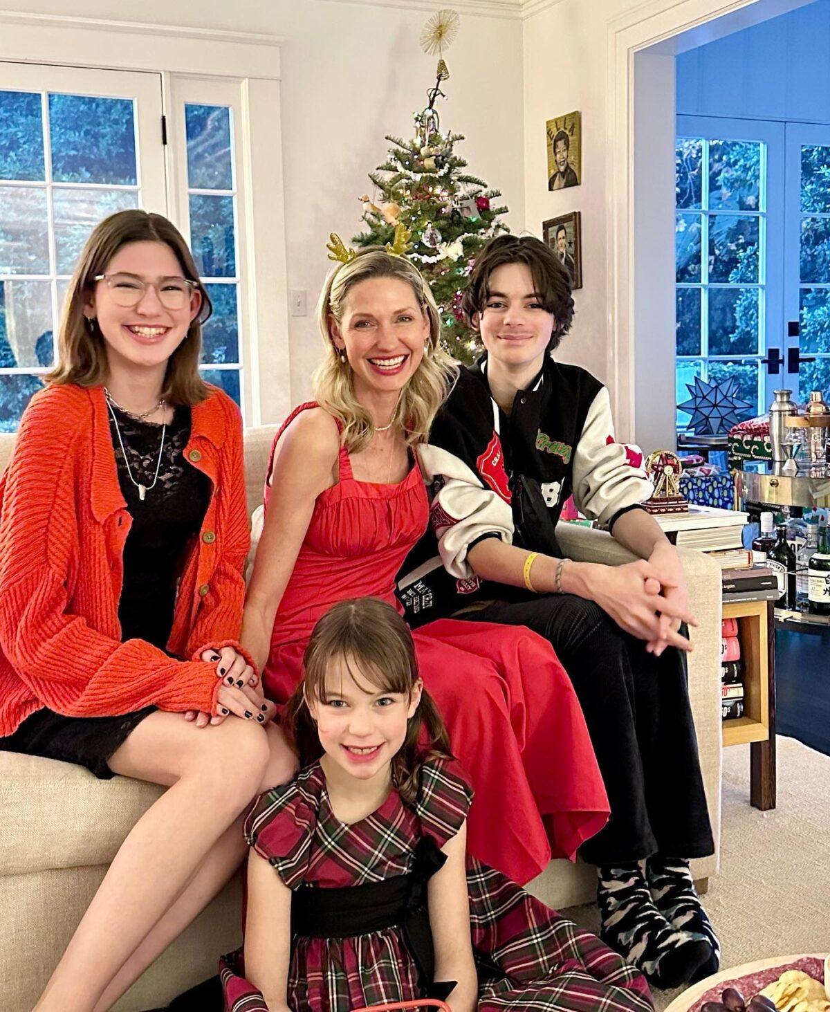 A family sitting on a living room couch in front of a Christmas Tree.