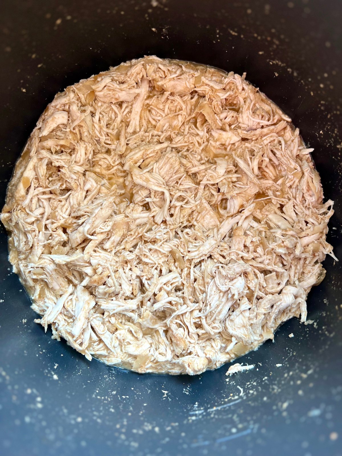 Shredded chicken in a slow cooker.