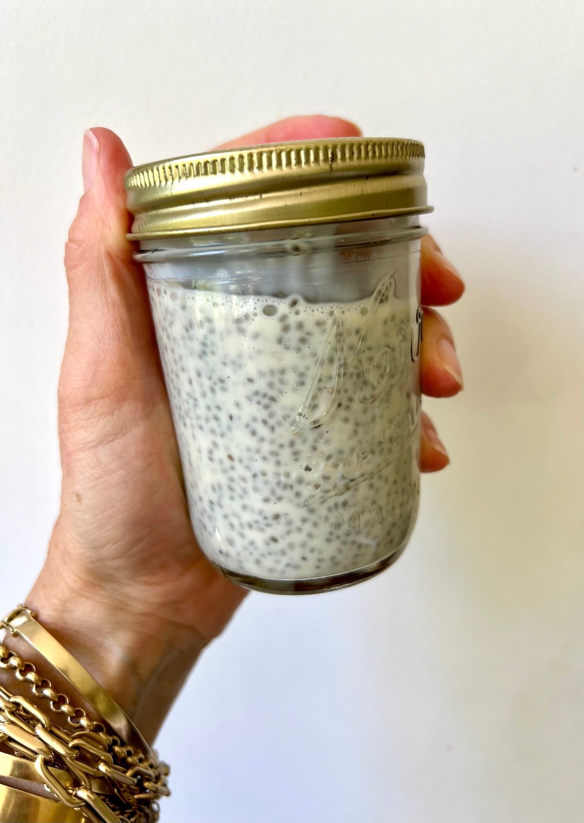 Hand holding jar of chia seed pudding.