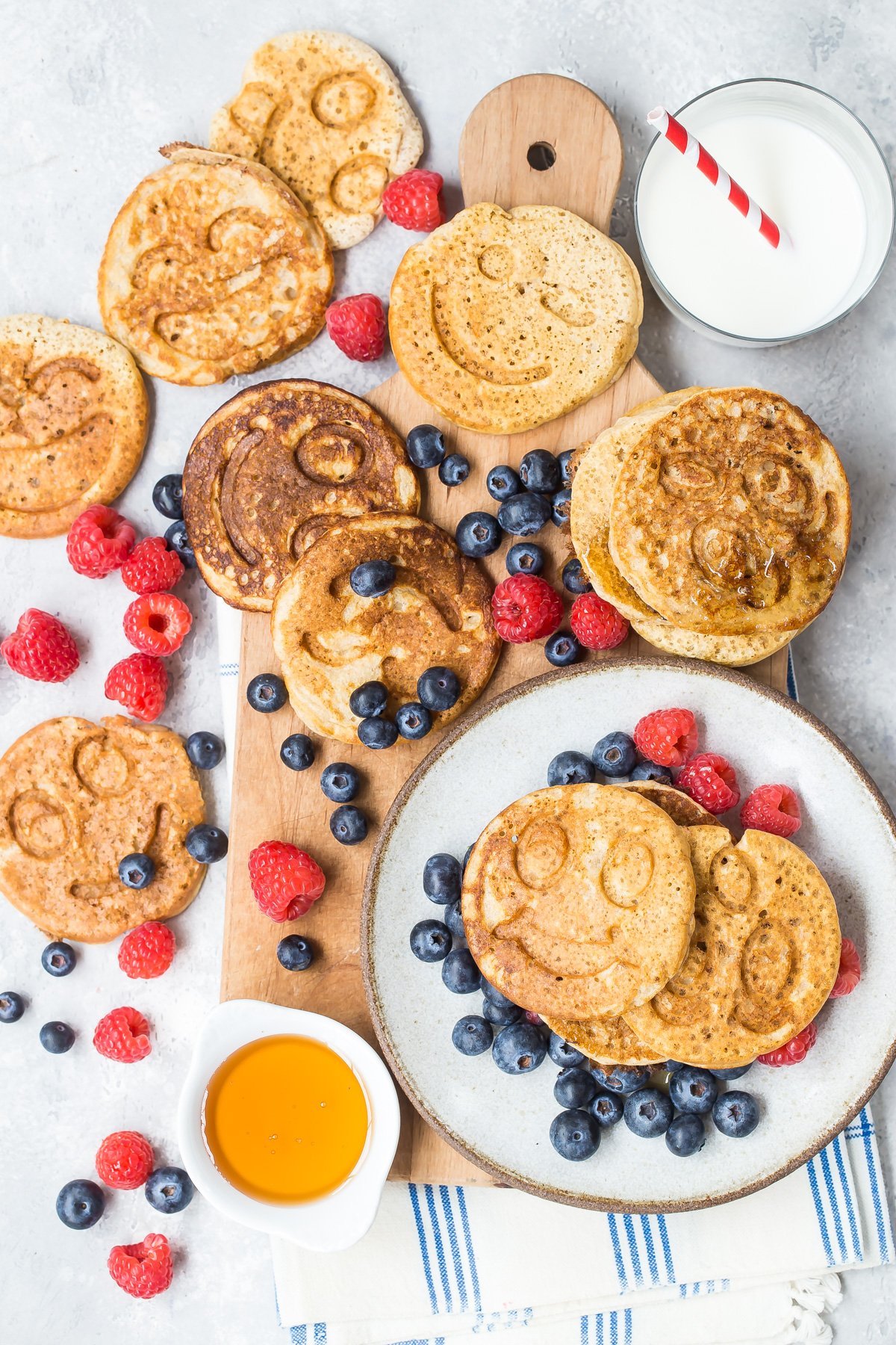 Quick oatmeal pancakes on serving platter surrounded by raspberries and blueberries.