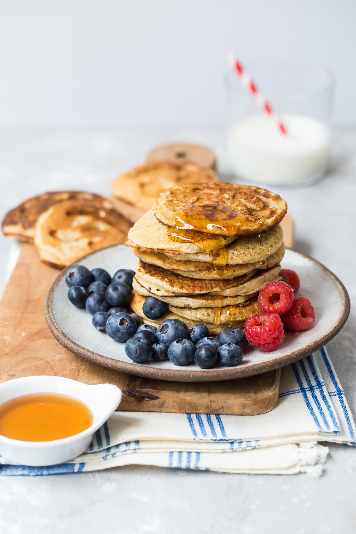 Quick oatmeal pancakes stacked on a plate with raspberries and blueberries.