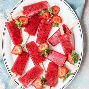 Strawberry popsicles on a plate.