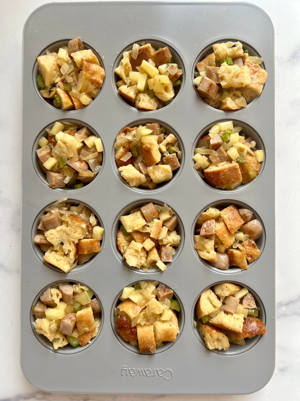 Stuffing mix in muffin tin cavities.