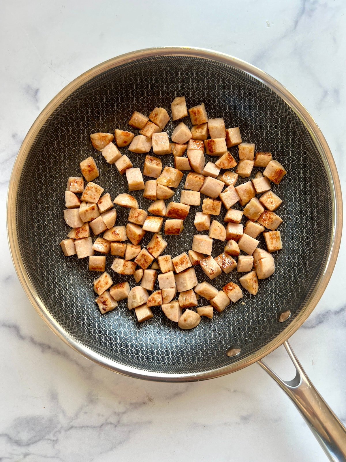 Diced sausage browning in a skillet.