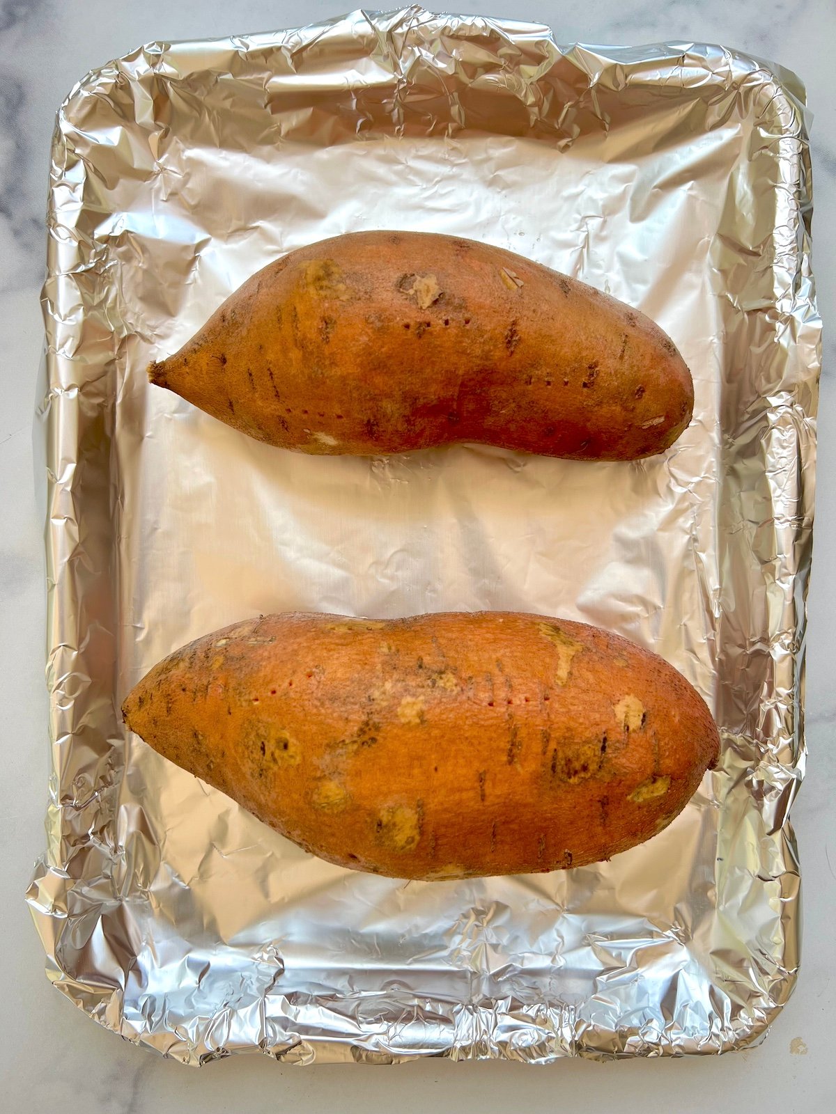 Sweet potatoes on a foil lined tray.