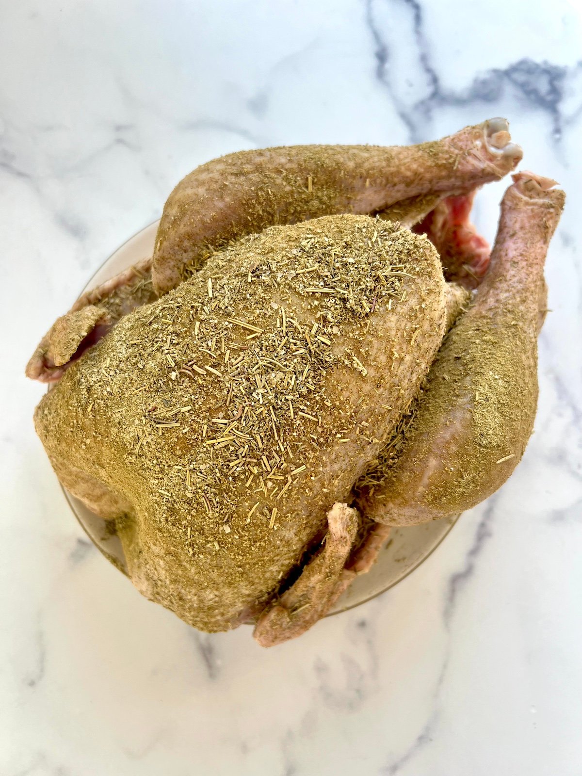 Herbs rubbed into raw turkey.