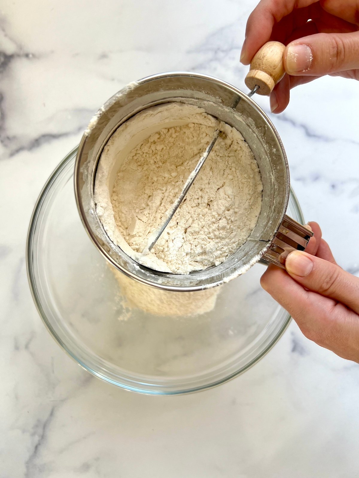 Dry ingredients in a sifter over a bowl.