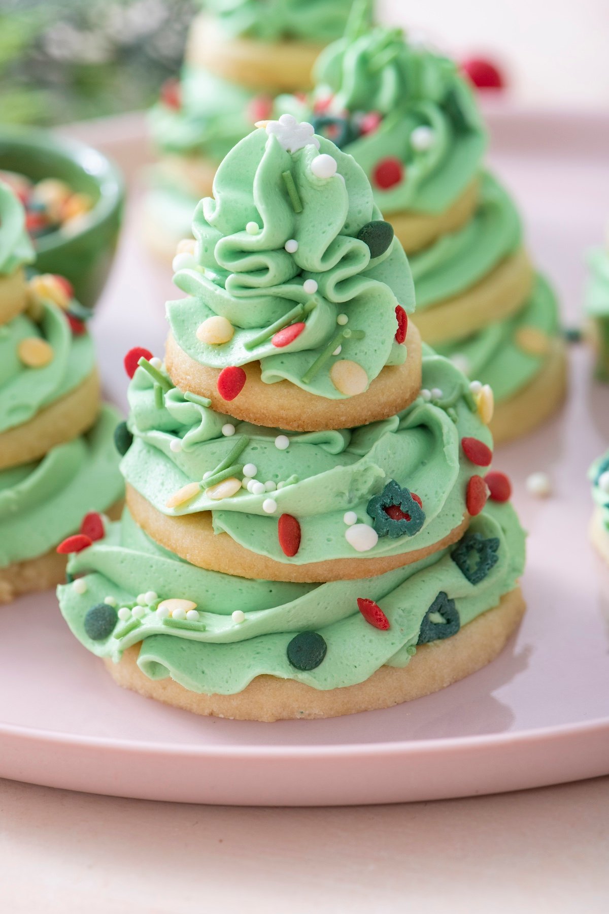 Sugar cookies stacked with swirls of green buttercream to create a Christmas tree shape.