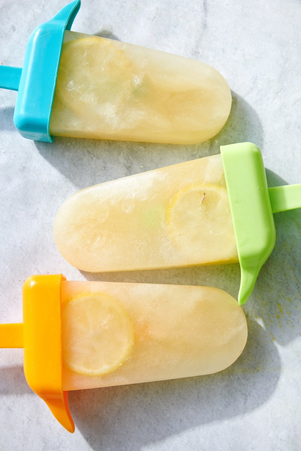 Three Wellness Electrolyte Popsicles on marble surface.