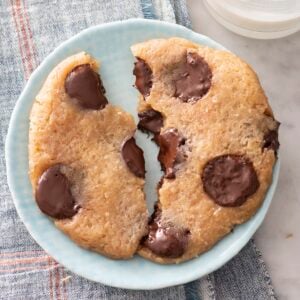 Microwave chocolate chip cookie broken in half on a plate.