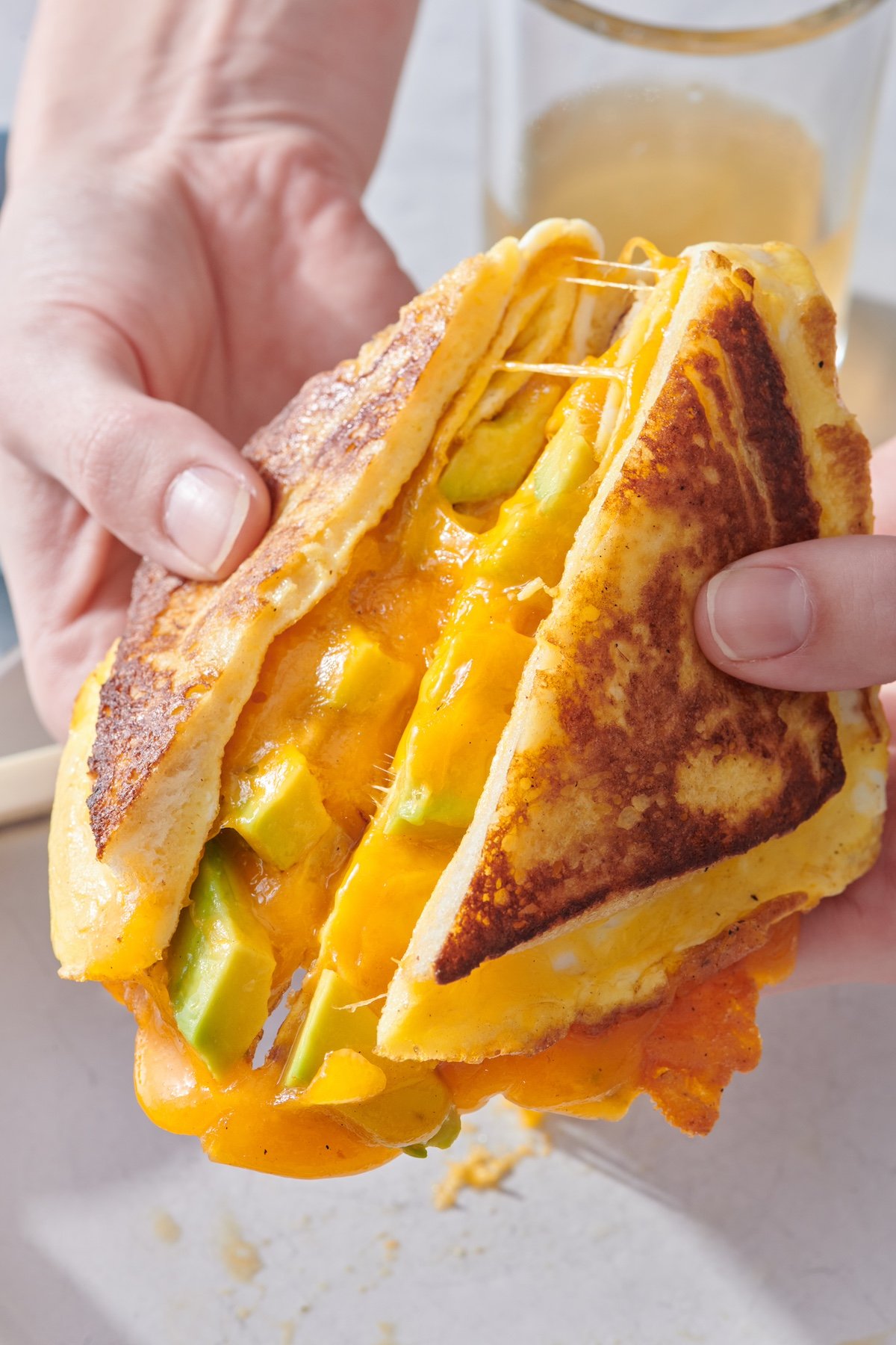 Hands holding breakfast sandwich.