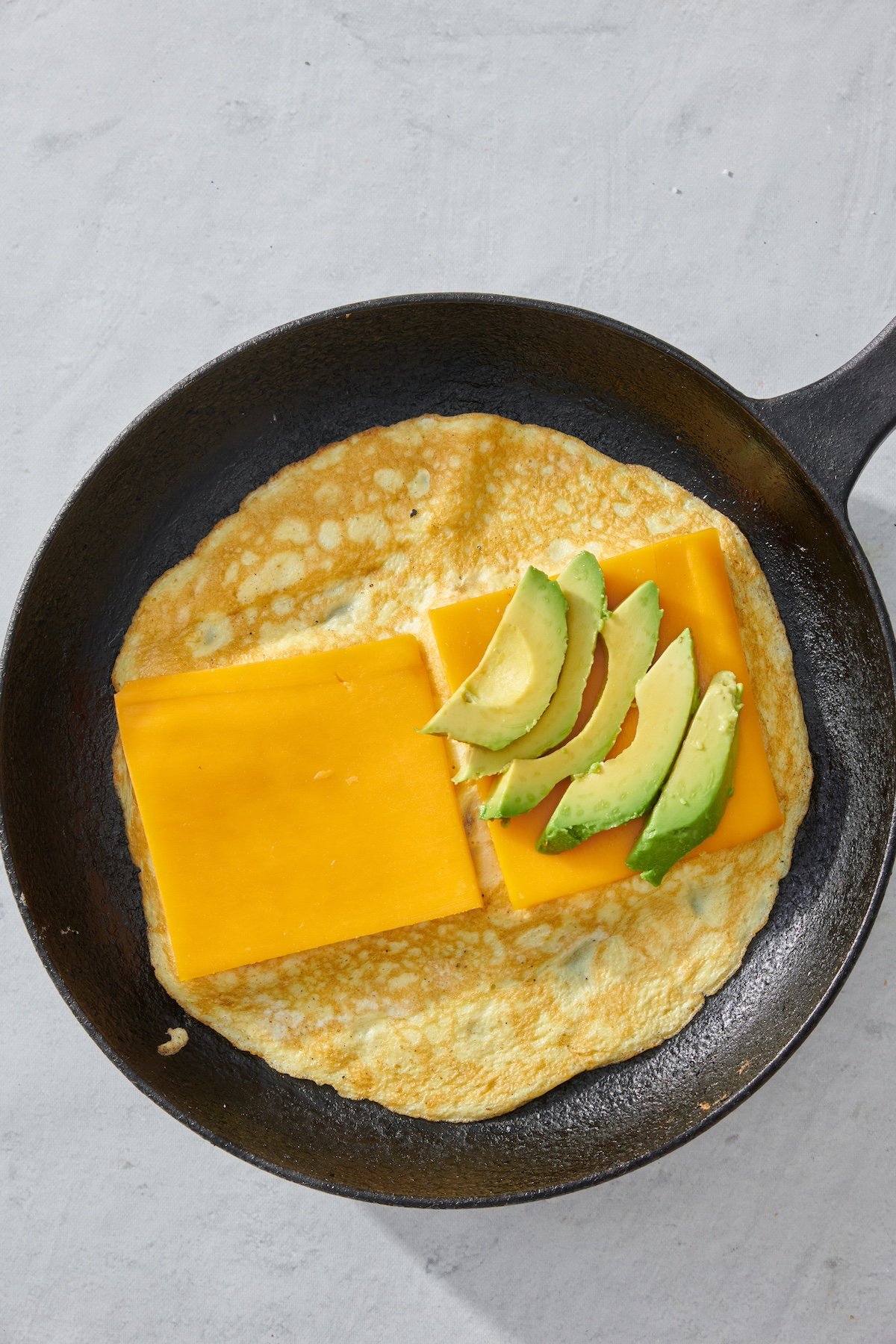 Sliced cheese and avocado layered on top of eggs.