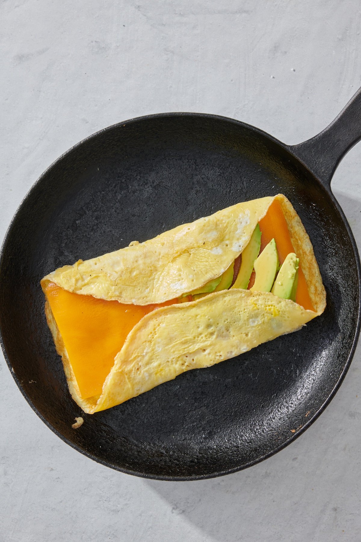 Folding in the edges of eggs to make the breakfast sandwich.