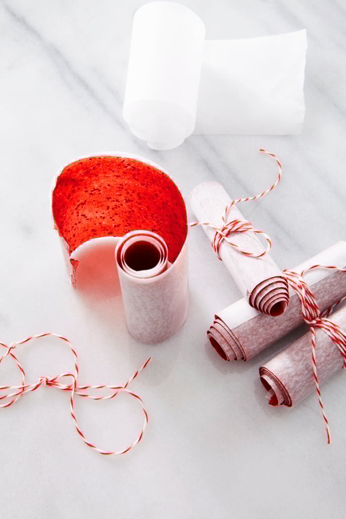 Strawberry fruit leather rolled up on parchment paper.