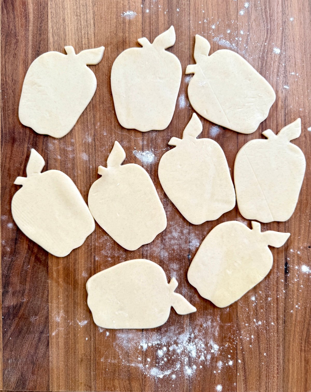 Apple shaped pie dough cutouts on a wooden surface.