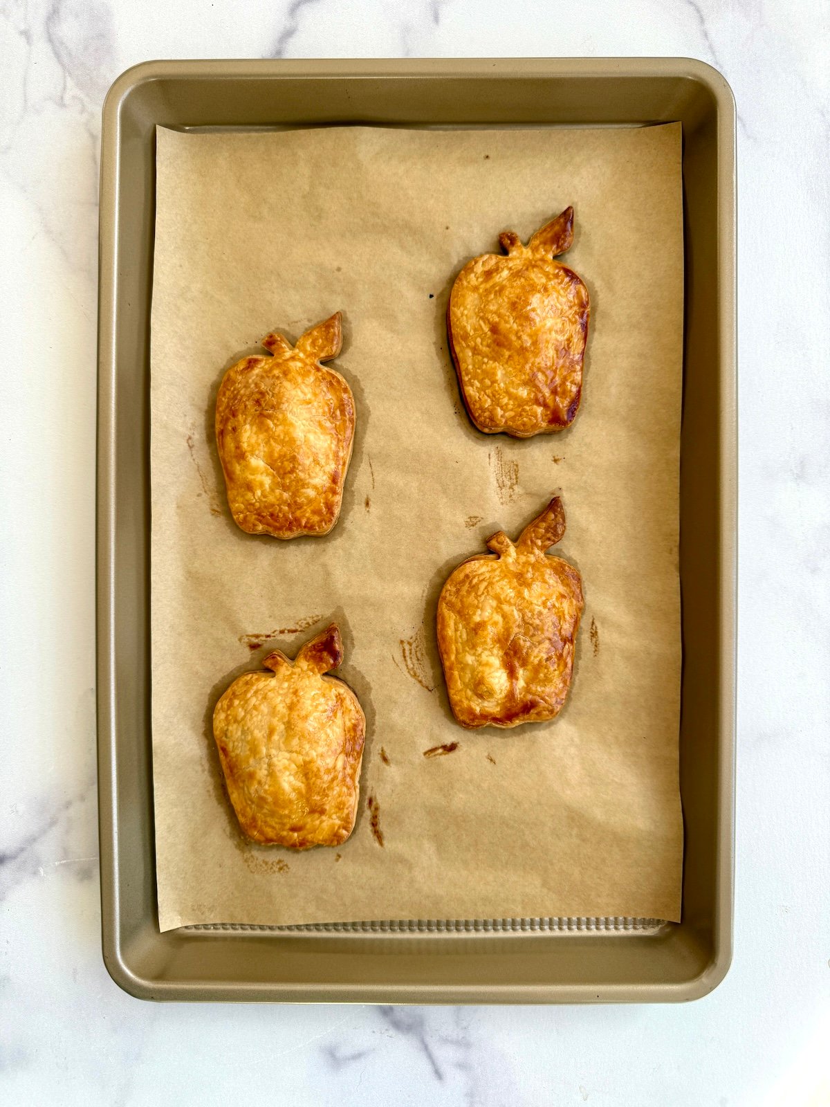 Baked apple pie turnovers on a baking sheet.