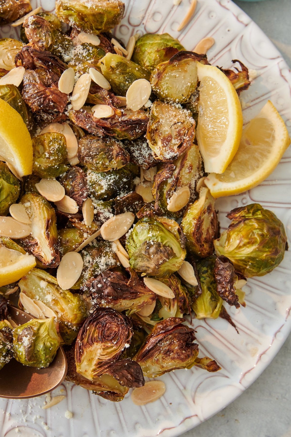 Roasted Brussels sprouts with sliced almonds, Parmesan cheese and lemon on a plate.