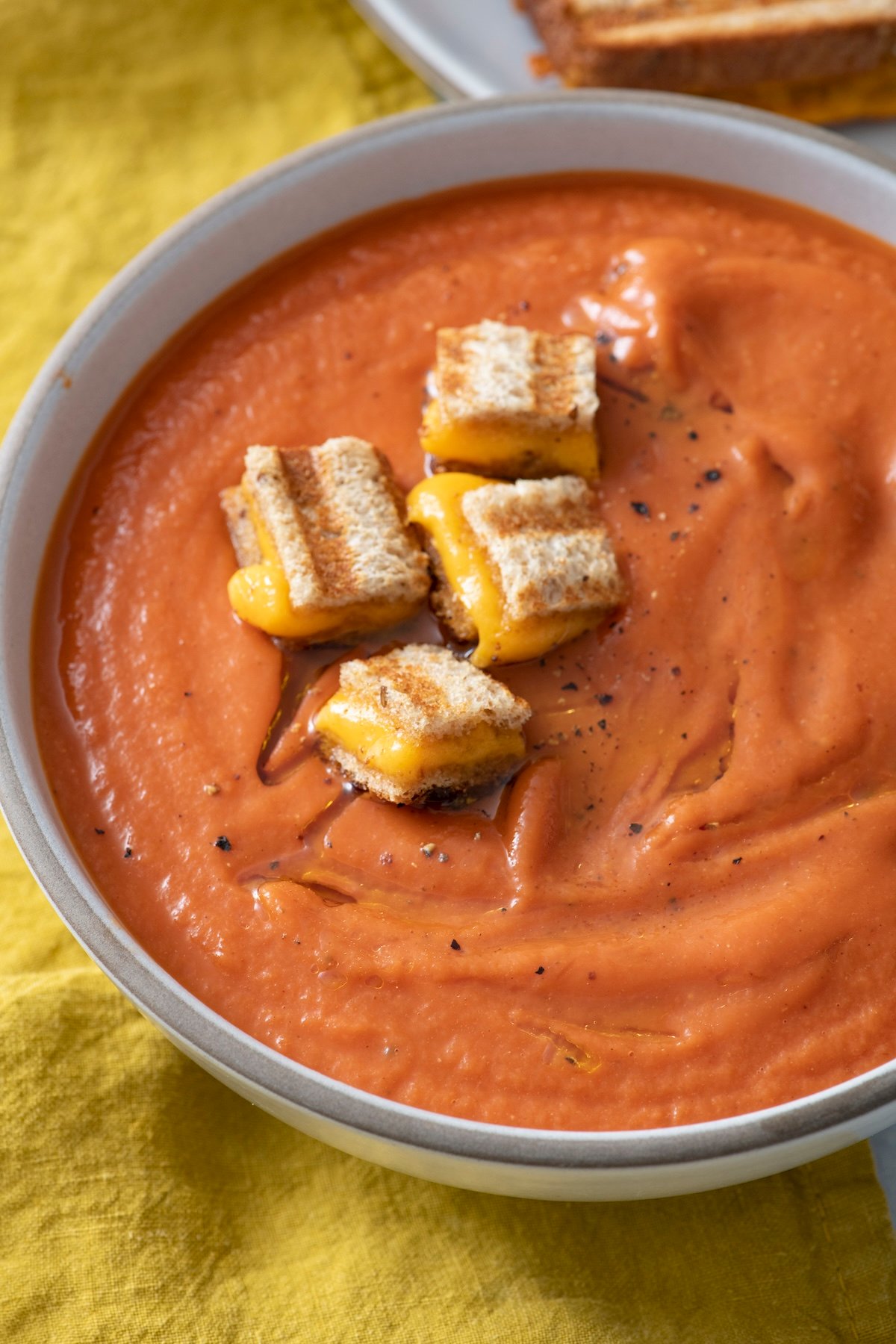 Roasted tomato soup with grilled cheese cubes on top.