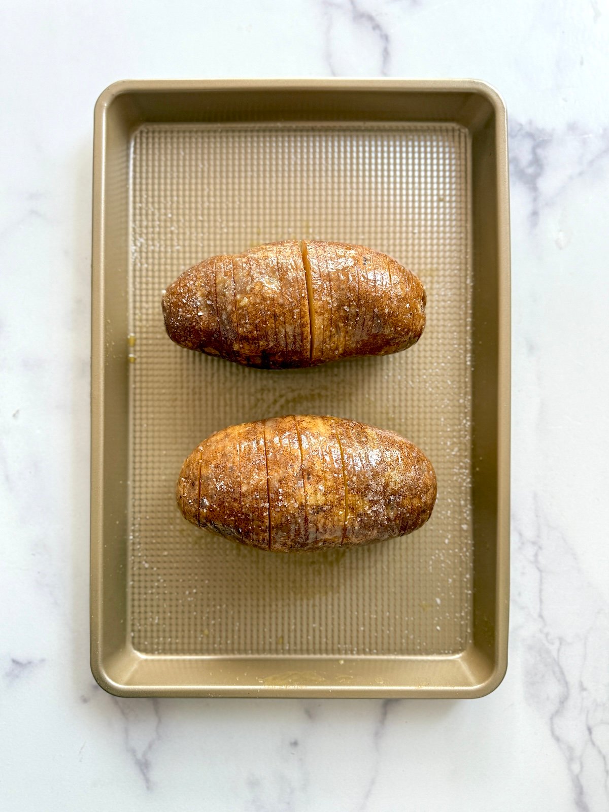 Hasselback potatoes on a baking sheet.