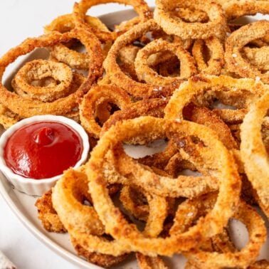 Onion rings on a plate with ketchup.