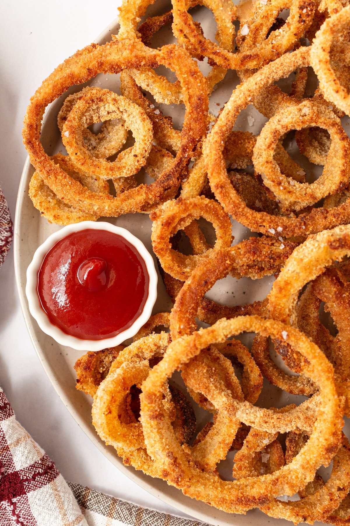 Crispy baked onion rings on a plate with ketchup.