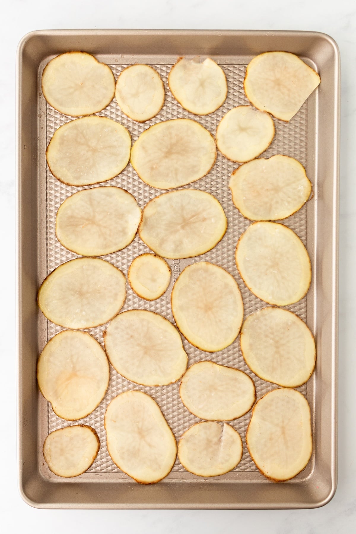 Potato slices arranged on a baking sheet.