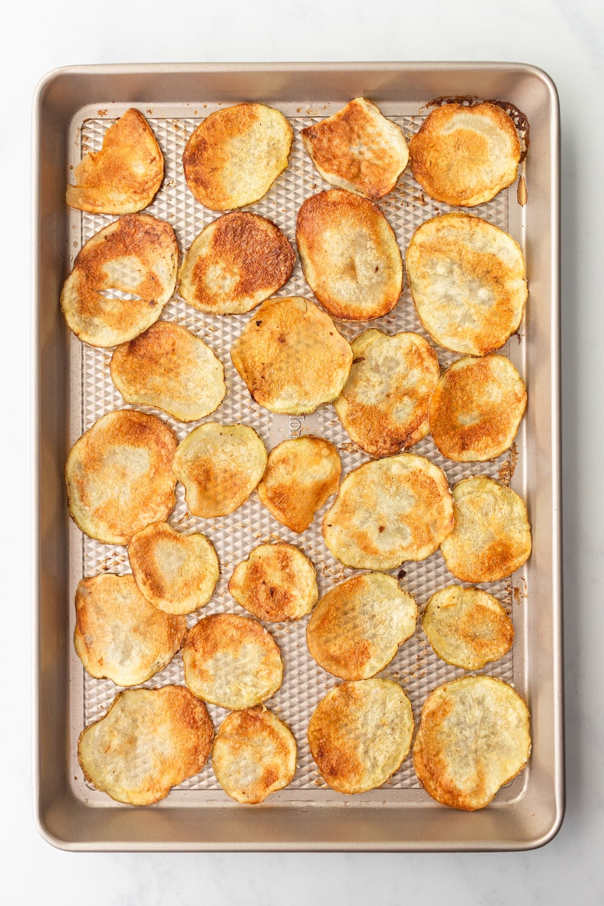 Crispy potato chips on a baking sheet.