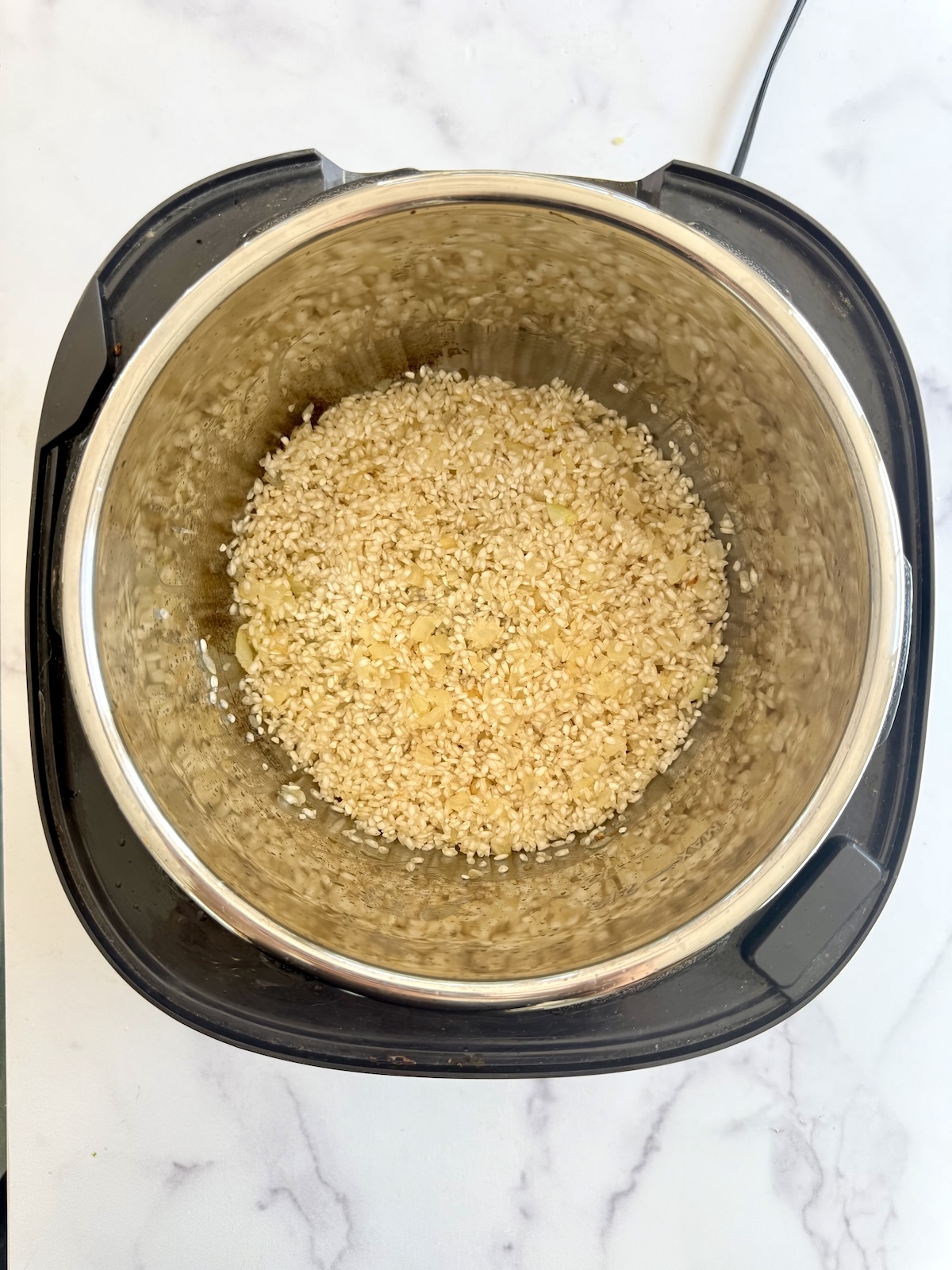 Toasting arborio rice in pressure cooker pot.