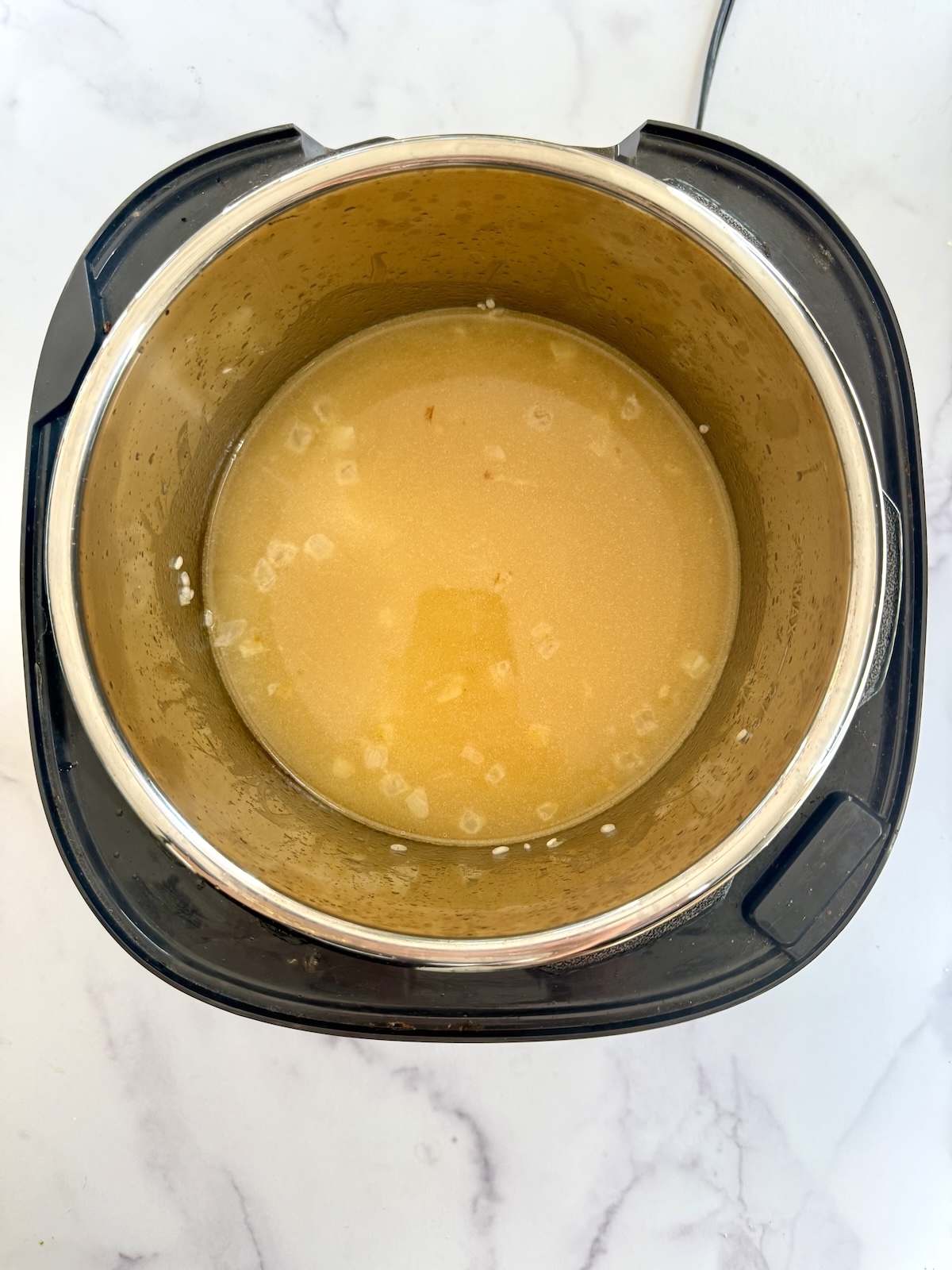 Pressure cooker risotto ingredients in pressure cooker pot.