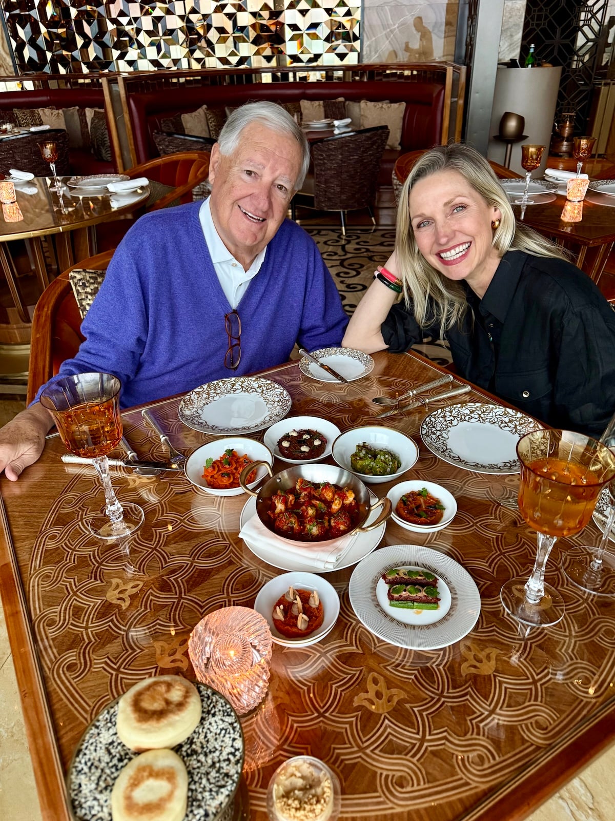 Catherine and her dad at a restaurant table filled with small Moroccan dishes and mezze.