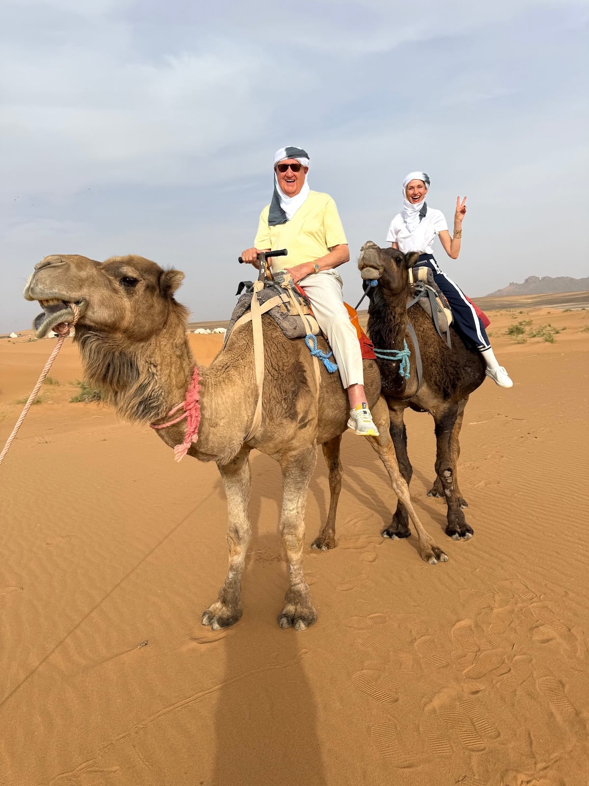 Catherine and her dad riding camels side by side through the dunes of the Sahara Desert.