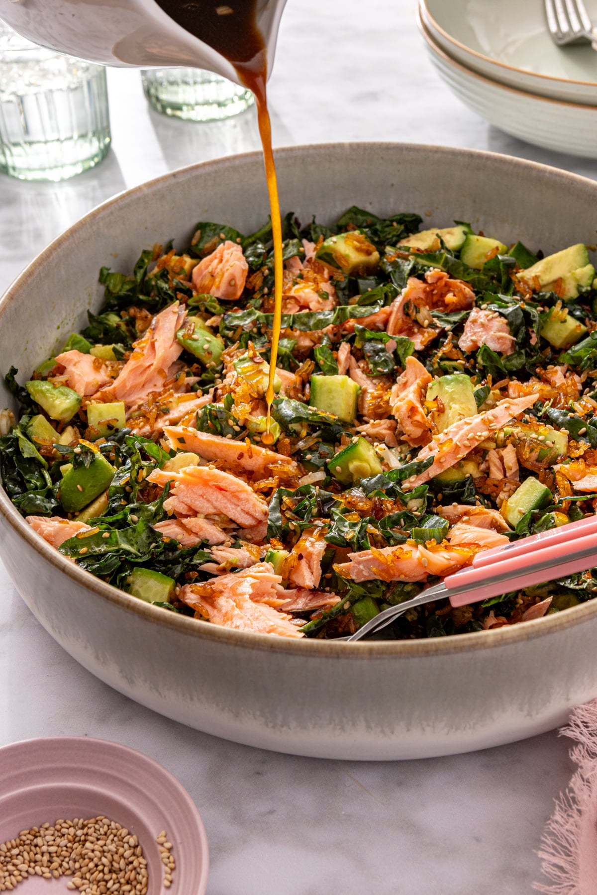 Sesame soy dressing being poured over finished crispy rice salmon salad in a large bowl.