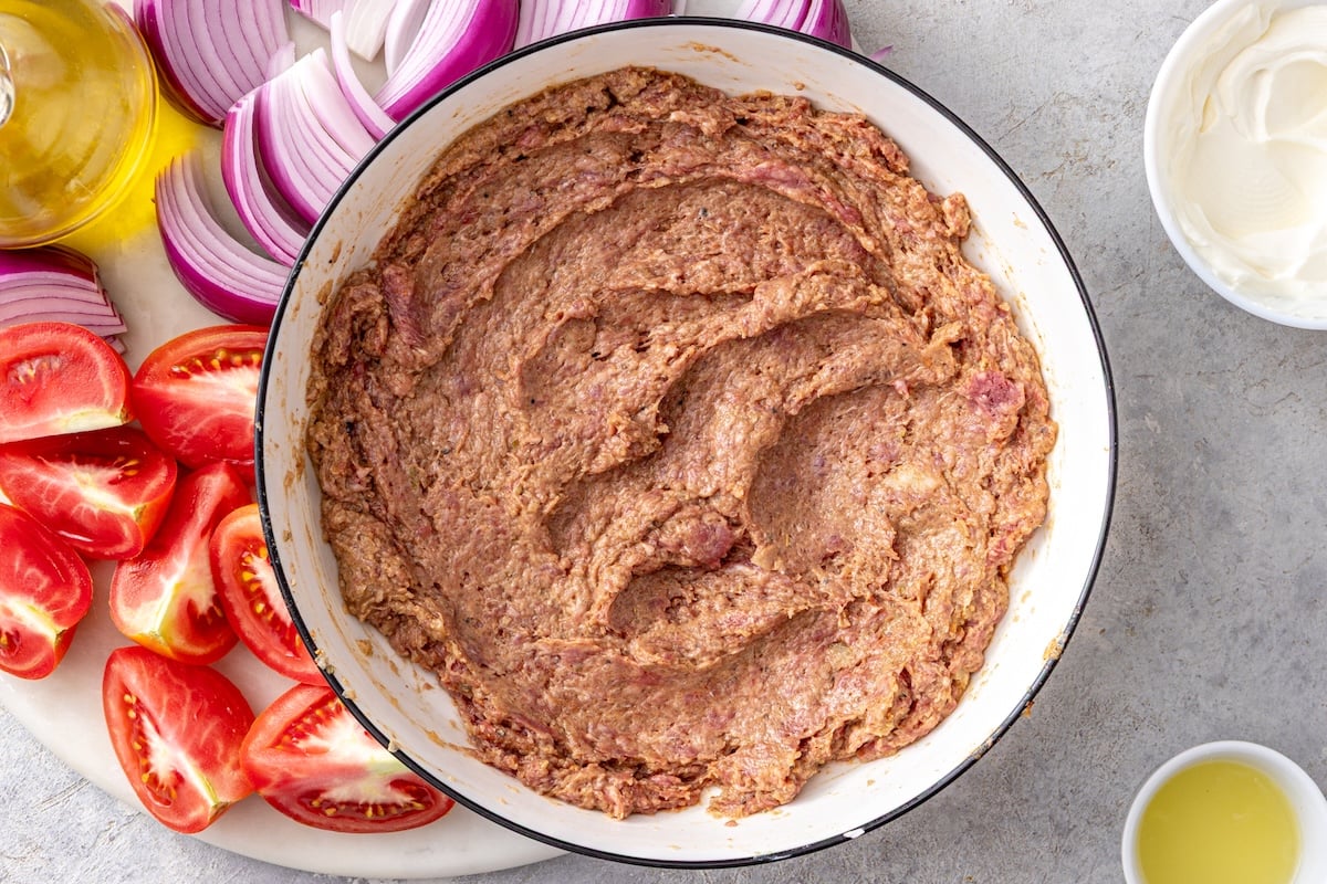 Ground beef mixed with Greek yogurt, smoked paprika, cumin, and spices in a large white bowl for doner kebab.
