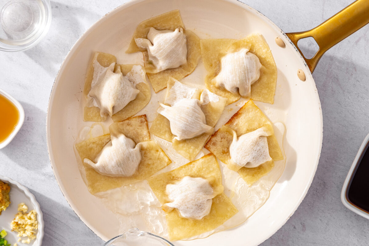 Assembled blanket dumplings in a skillet with water before steaming.
